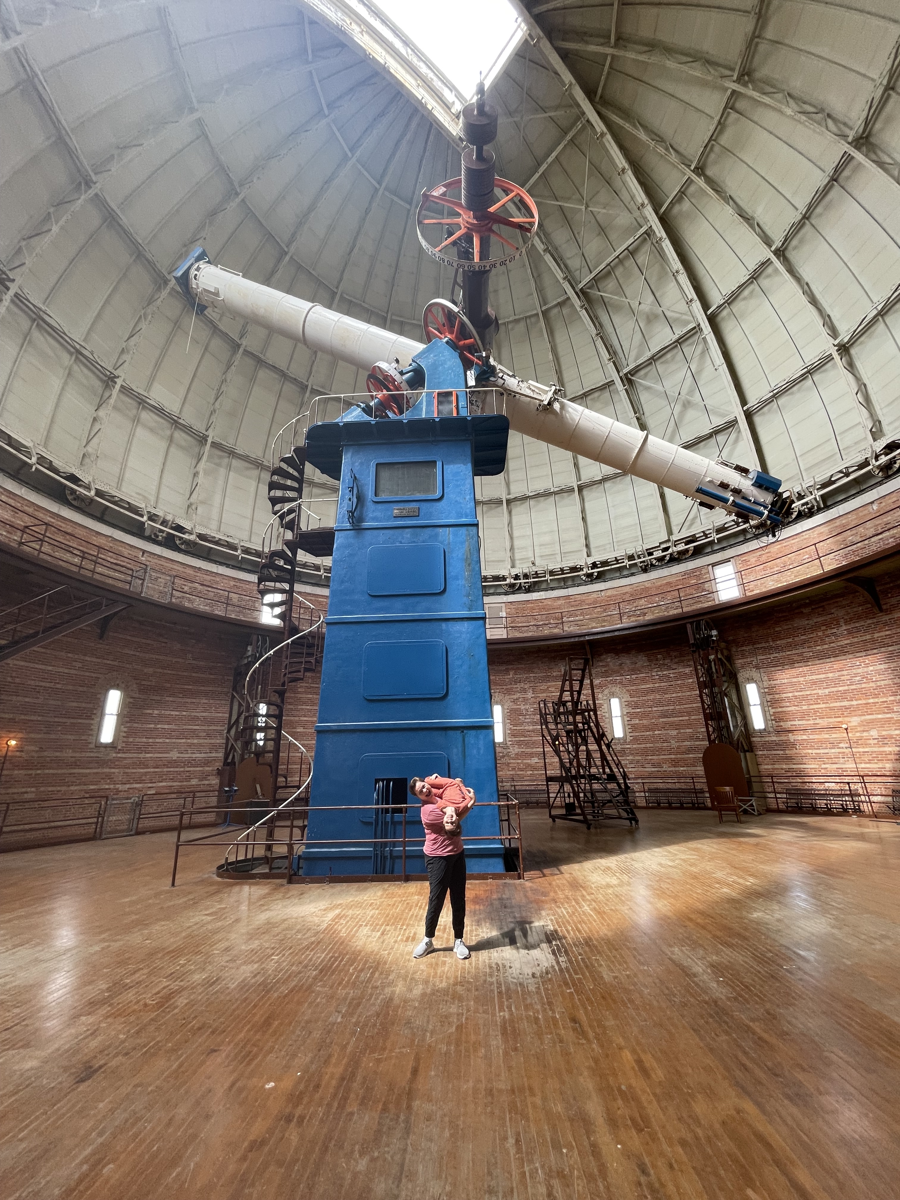 Standing with my kid (who is upside down over my shoulder) in front of the giant 40" refracting telescope at Yerkes Observatory.