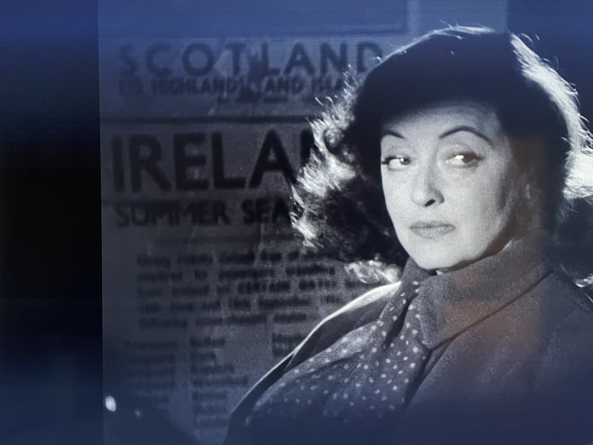 From ‘Another Man’s Poison’ - Bette Davis not reading an Ireland Summer Season by rail poster.