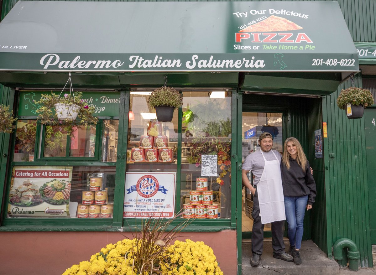 JerseyCity's tweet photo. Husband and wife team Connie and Maurice Henriquez stand in the doorway of Palermo Italian Salumeria at 420 West Side. Opened in March 2020 and serving authentic food, they make everything from soups and sandwiches to pizza fresh in house and also offer catering. #JCstorefronts https://t.co/Uc9sds7Vkt