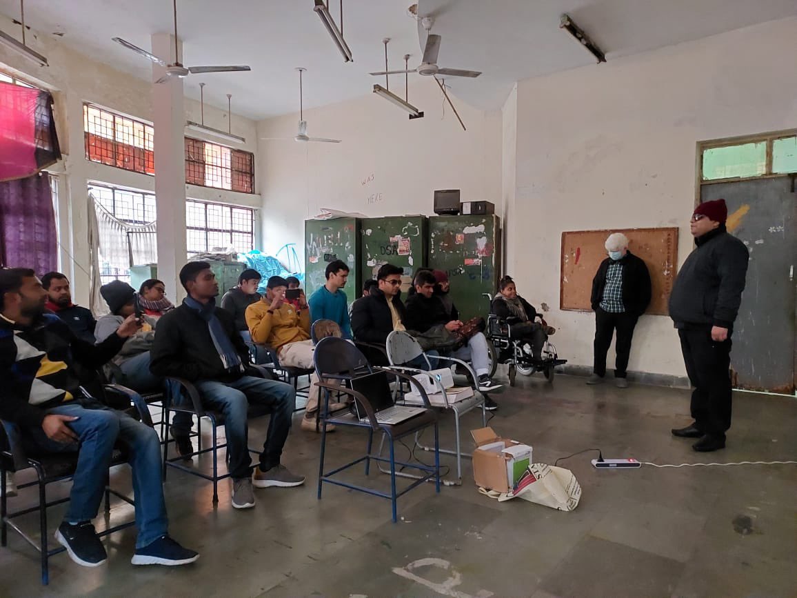 One of our members Mukesh Singh is delivering his address to the audience on the significance of Braille language. The audience is sitting on chairs in front of Mukesh.