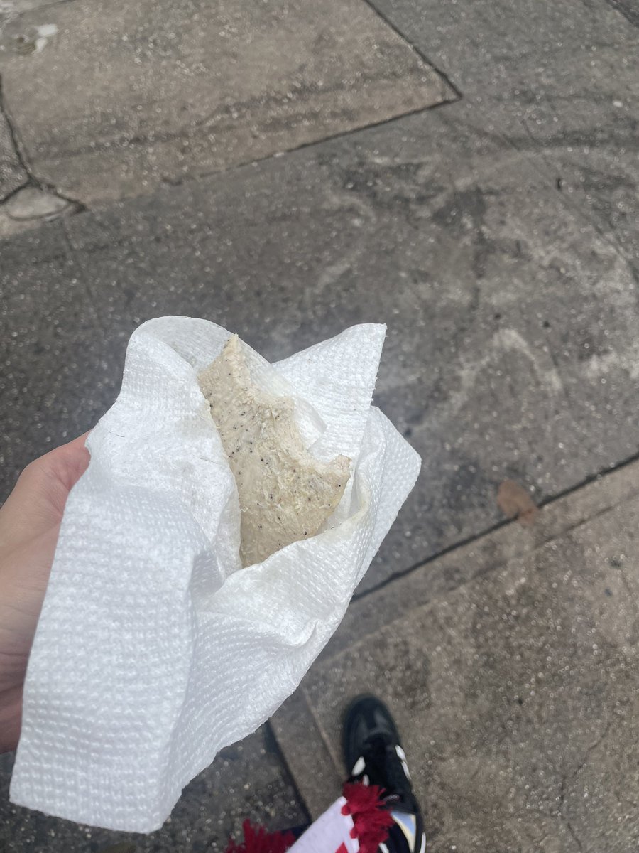 Eating a piece of chicken wrapped in a napkin walking down the street