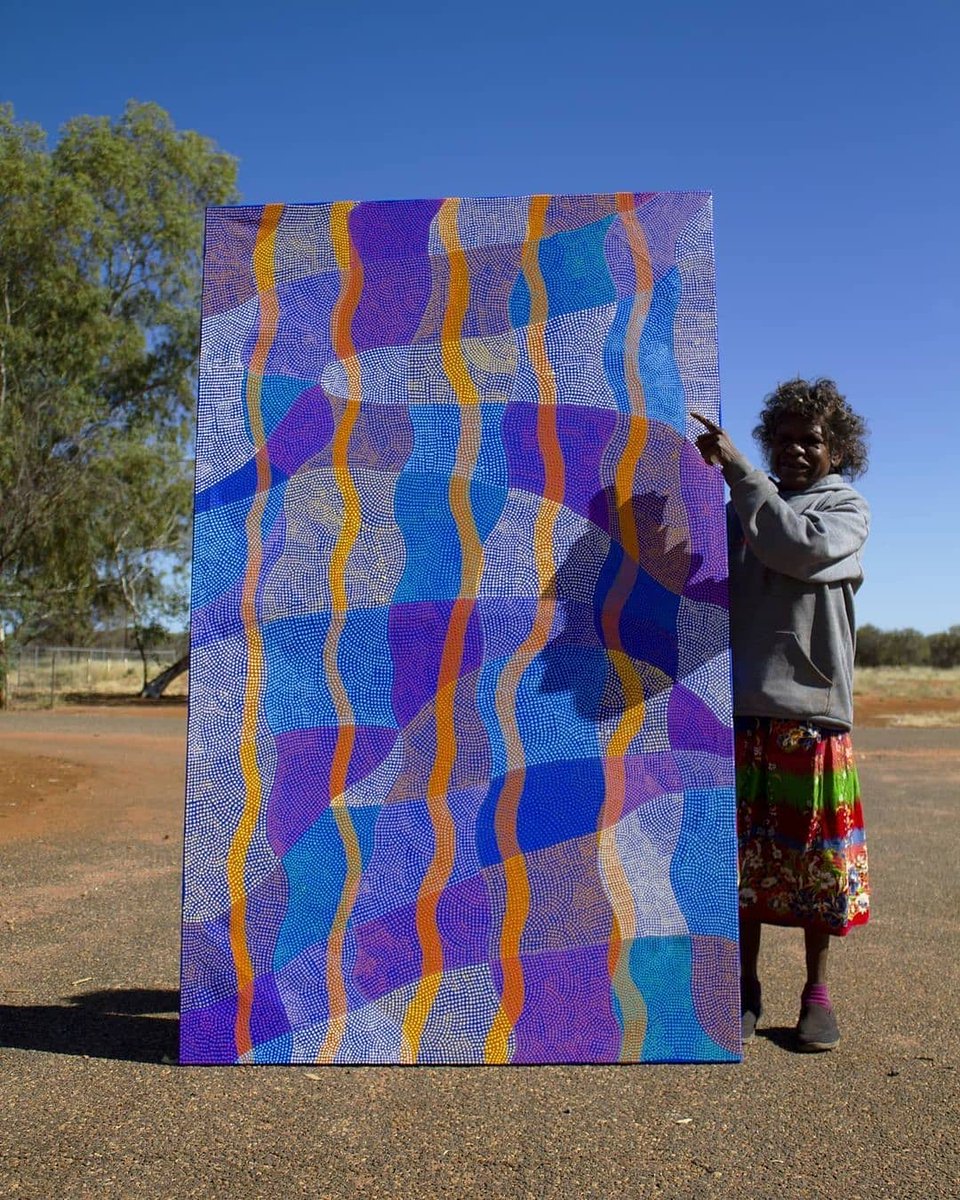 This Is artist Ann Lane from @ikuntjiartists. Ikuntji Artists was the first art centre established by women in the Western Desert Art Movement. Located 230km west of Alice Springs, Ikuntji Artists is featured in the Red Centre Art Guide on our website: bit.ly/3Qb9dUM
