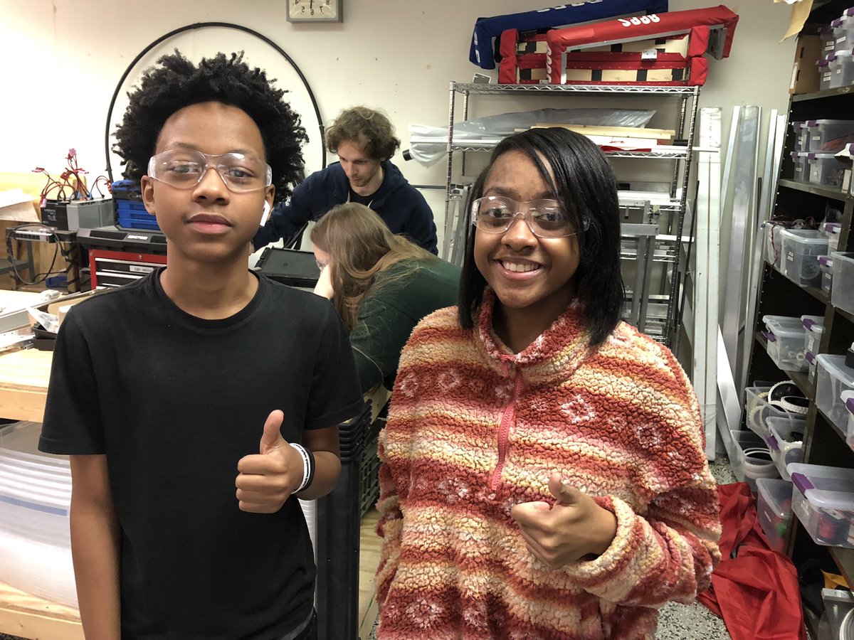 Robotics is great for siblings! Students James & Brittany give a thumbs up while mentors Holland and Ashton check out build equipment in the background. #weareRPS #TJHSroboticsRVA #FRC2998 #TJHSrobotics