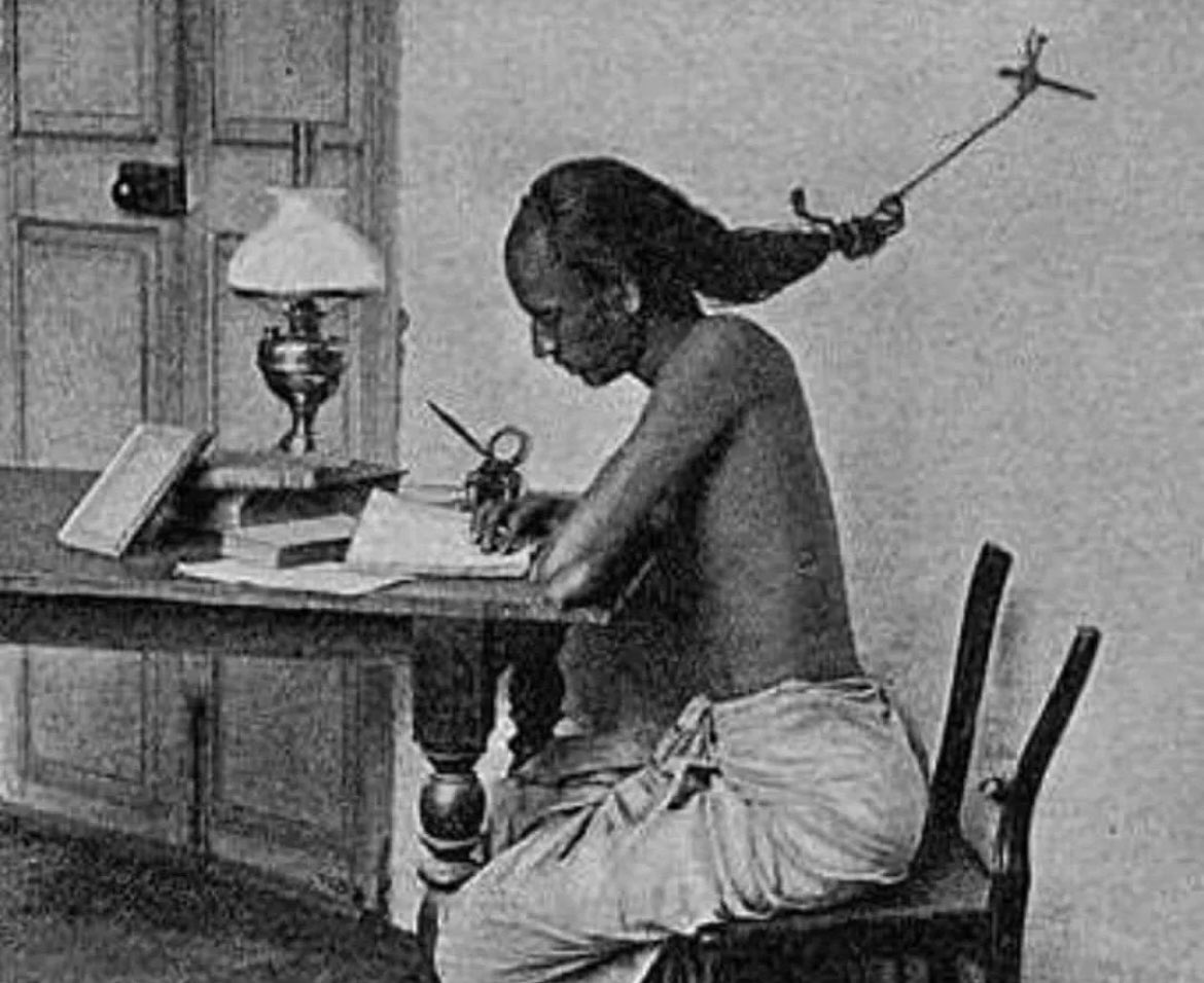 An Indian student studying at the University of Madras in Tamil Nadu, 1905. While studying late at night, students use to tie their hairs to a nail in the wall to prevent themselves from falling asleep.