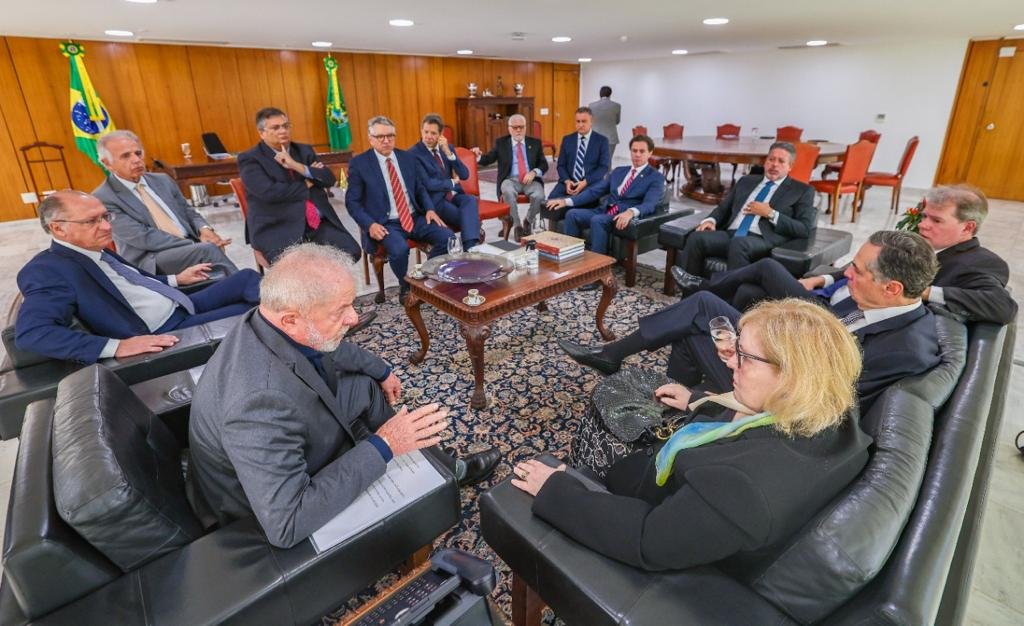 Representantes dos poderes sentados em reunião no gabinete presidencial. Observam Lula falar
