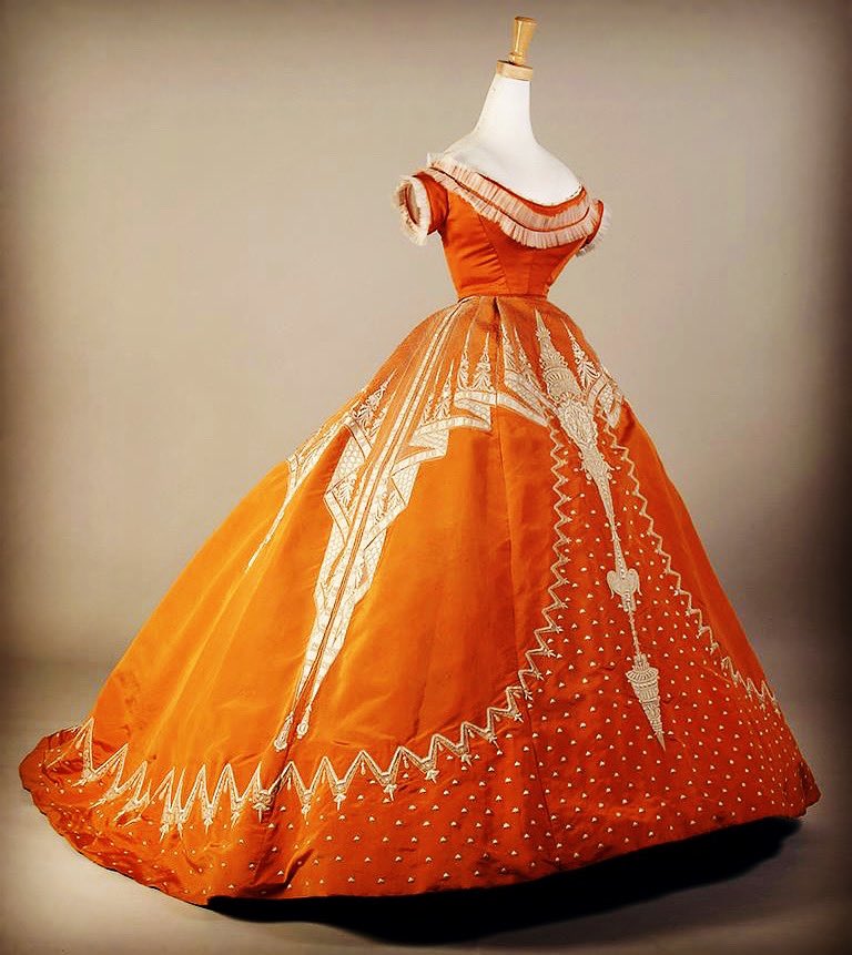 kateStrasdin's tweet photo. A great ball of orange warmth to brighten January drizzle. This mid #1860s favourite features a trompe l’oeil lace effect decoration, an early design by the #HouseofWorth hinting at the innovative textile treatments that would follow @KSUMuseum #fashionhistory https://t.co/RvjkXi3OAX