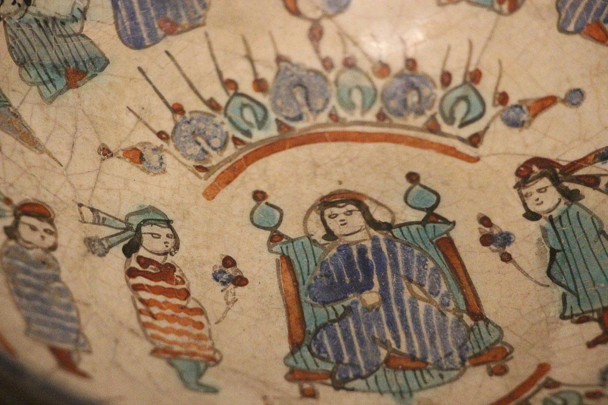 白釉をかけた素地に黒で輪郭をとり、赤、青、ターコイズ色などで人物文