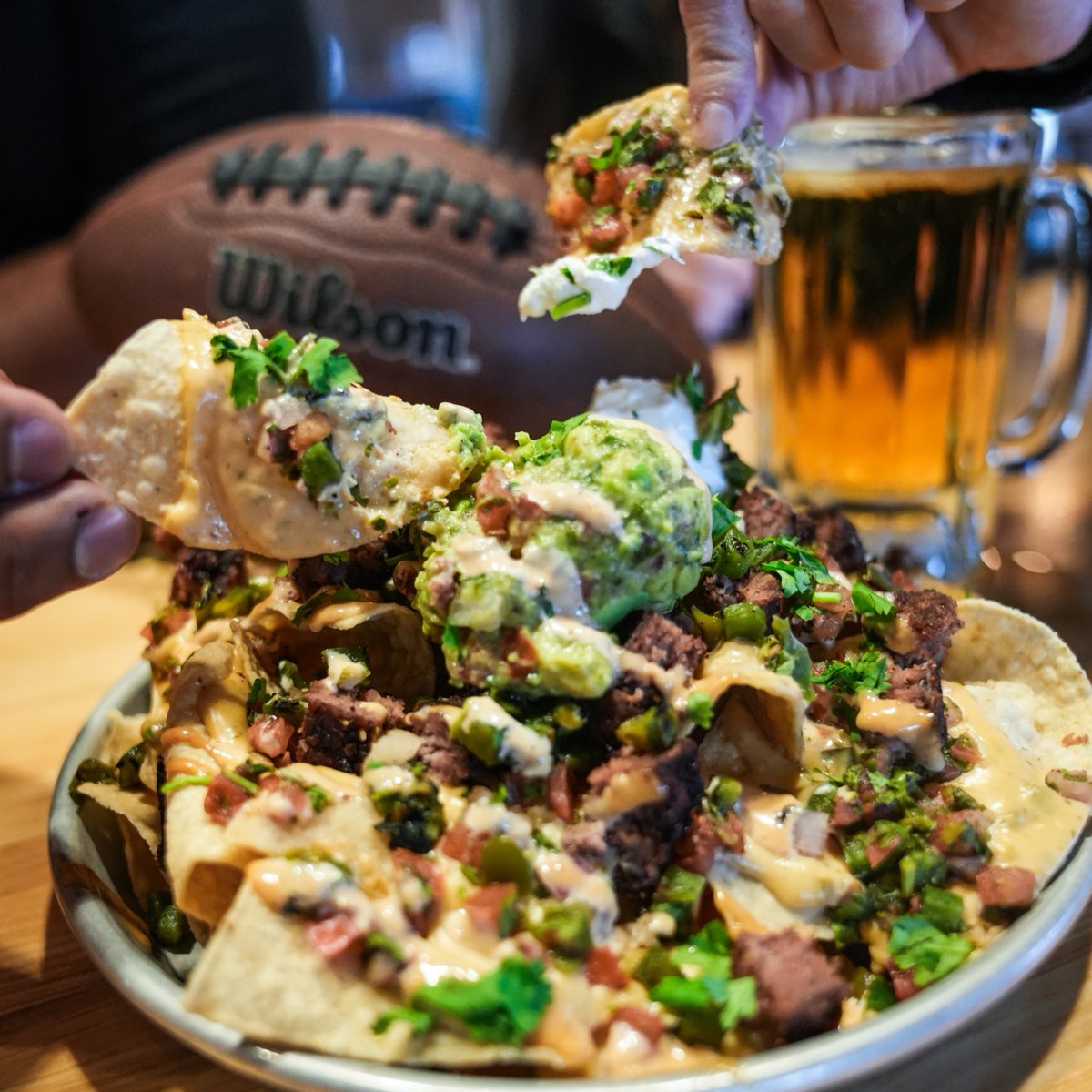 Loaded Nachos are coming in hot! 🏈 Every bite is piled high with chipotle queso, pico de gallo, diced jalapeños, guacamole, sour cream, cilantro, chipotle aioli &amp; chopped beef patty for the perfect snack during those Wild Card games this weekend.