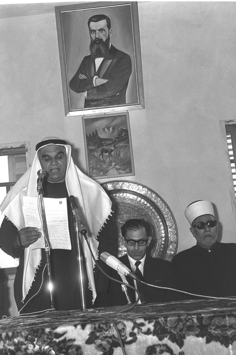 صورة من عام 1970 لعضو الكنيست الشيخ جبر معدي وهو يلقى كلمة في منزله، بجوار وزير الداخلية...