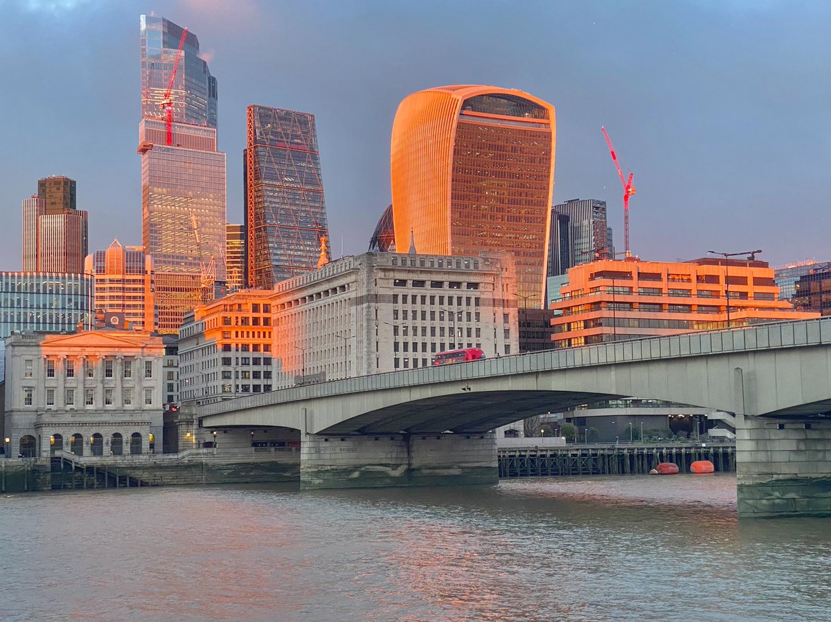 MrTimDunn's tweet photo. As I walked home along the river tonight, the rain paused, so I paused too. We – a handful of strangers – watched in silent awe as Golden Hour magic swept over the Square Mile; and a defiant red double-decker sailed across the bridge, off into the dark canyons of the City beyond. https://t.co/WfDNvd9ebt