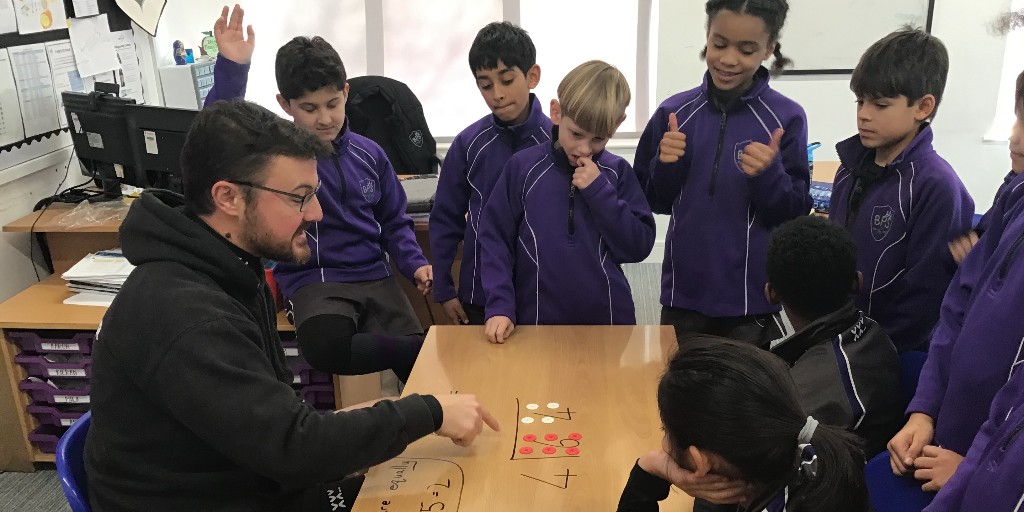 BansteadPrep's tweet photo. Innovating like a pro, Mr Jeens and #Year4 are taking the hands on approach to the bus stop method in #maths.  By writing on the tables and using counters to aid understanding, engagement with learning is high! #mathsmastery #moderneducation #expecttheunexpected #curiosity https://t.co/eUMazU3WmR