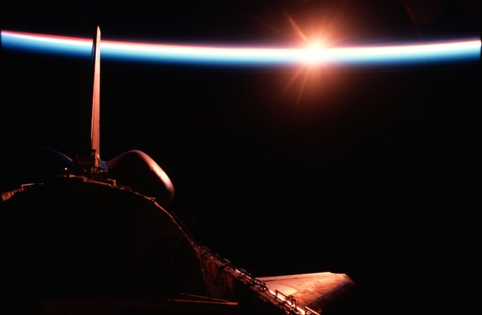 The space shuttle Columbia passes into a brilliant sunrise scene during the STS-9\Spacelab 1 mission. The photograph was taken with a 35mm camera aimed through Columbia's aft flight deck windows. Part of the science module, which hosted more than a week's scientific experimentation, is silhouetted against the scene. Credit:NASA