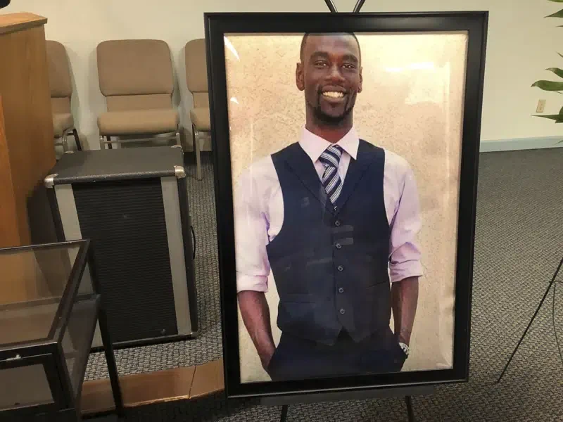Picture of Tyre Nichols, a young Black man in a suit vest and tie, displayed in a funeral home during his memorial. 