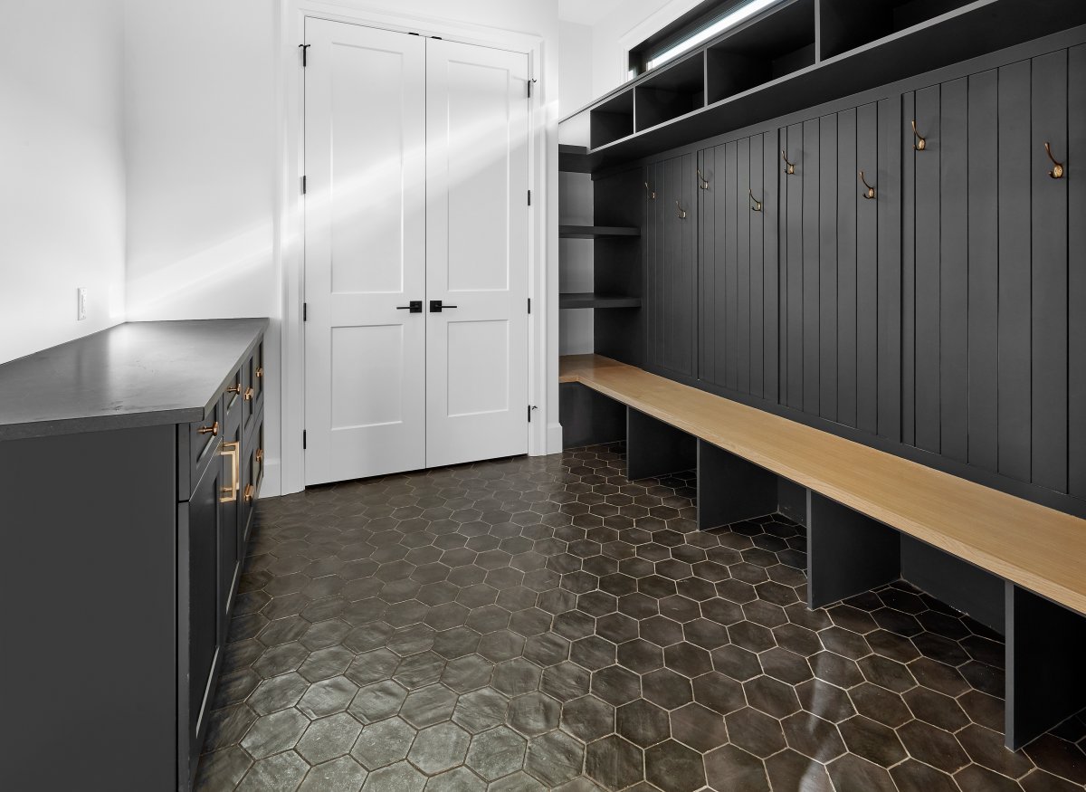We love this moody monochromatic mudroom.

Dark finishes, complimented with the warmth of white oak and sophisticated gold hardware.
