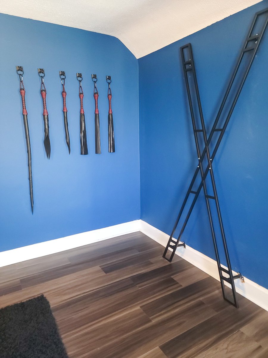 WantonSinners's tweet photo. The wall of floggers and whips looms imposingly, the leather tools of pleasure glinting in the light. Nearby stands a St. Andrew's cross, its four arms reaching out in invitation. The smooth metal is inviting to the touch and promises a safe and secure experience. #tellusyoursins https://t.co/kT8hEYpV74