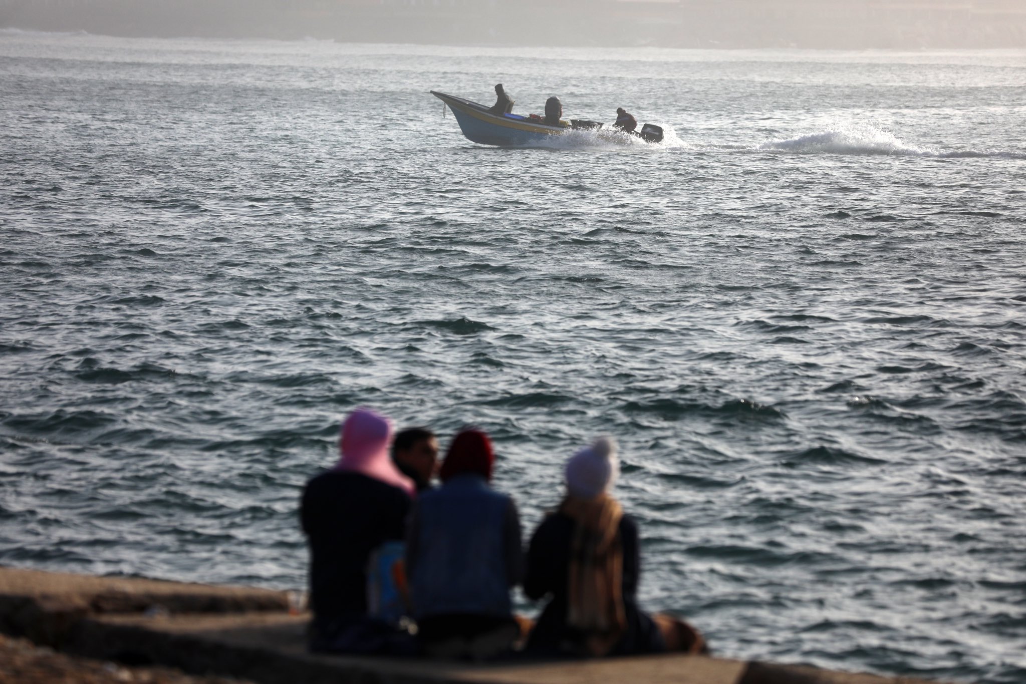 نساء فلسطينيات من قطاع غزة يراقبن حركة المراكب على الشاطئ 