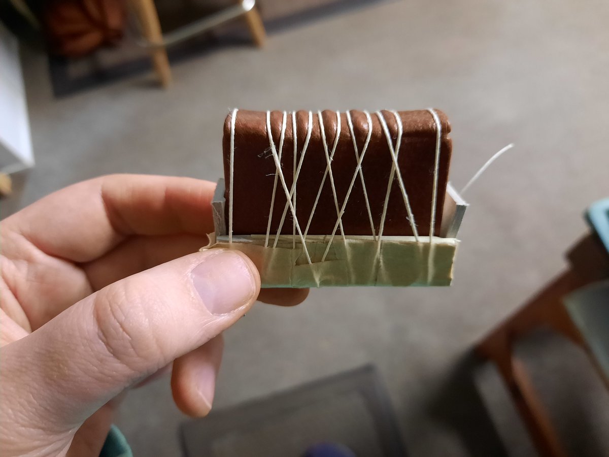 ariellesbindery's tweet photo. A miniature book covered in leather and tied up on a makeshift tie up press. I think the bands might have been sewn a little too close together but it doesn't look too bad when it isn't covered in thread! 😁 https://t.co/QkInoFcDtD