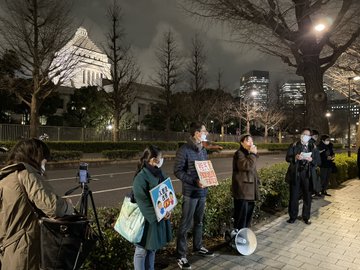 小雨が降りしきる中、国会に集まった抗議する市民