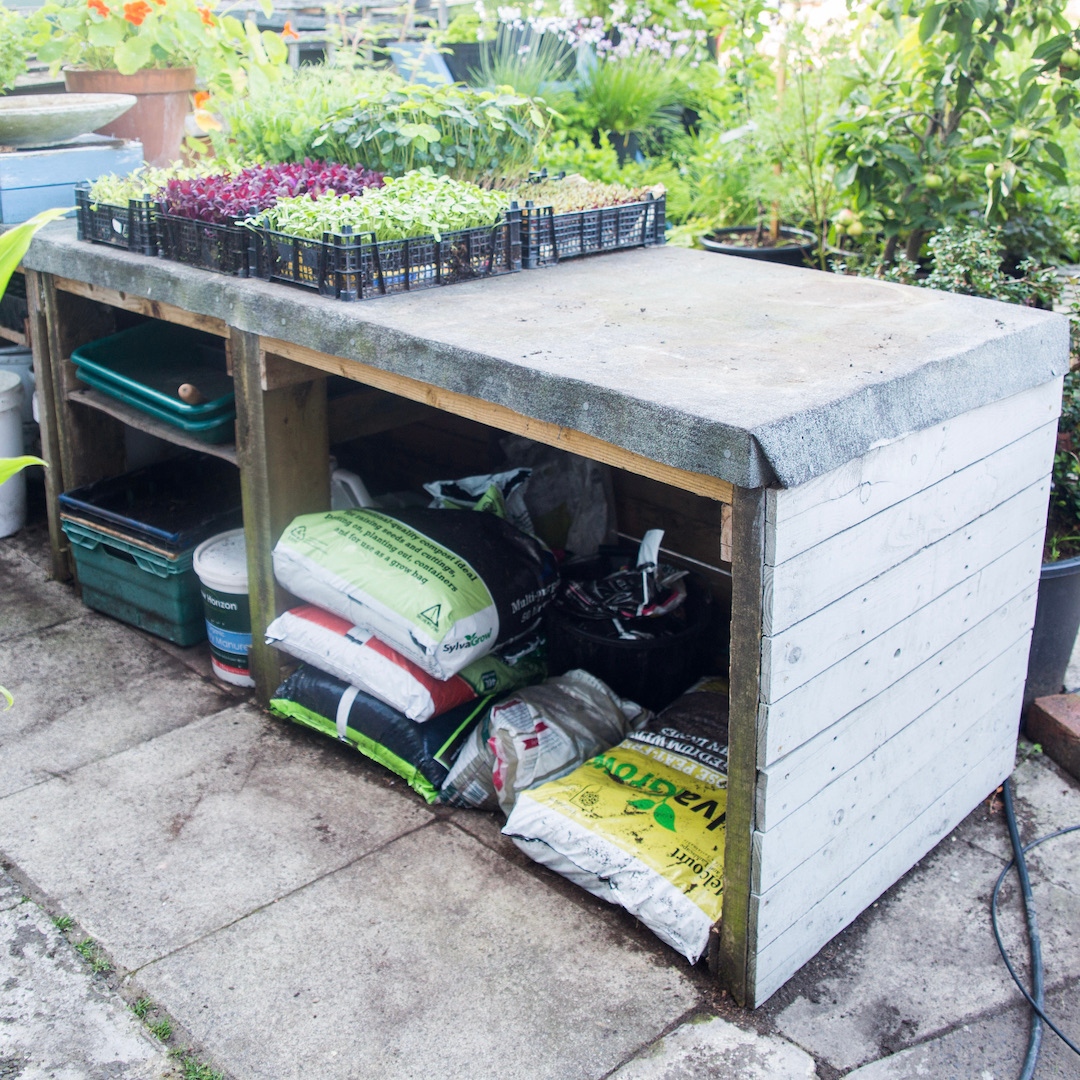 Lack of both growing and storage space is a common challenge. Sometimes both can be addressed by a simple structure. 

Here's one I made. The top is a potting bench, and a microgreen growing area. Underneath there is storage for bags of compost and empty pots.