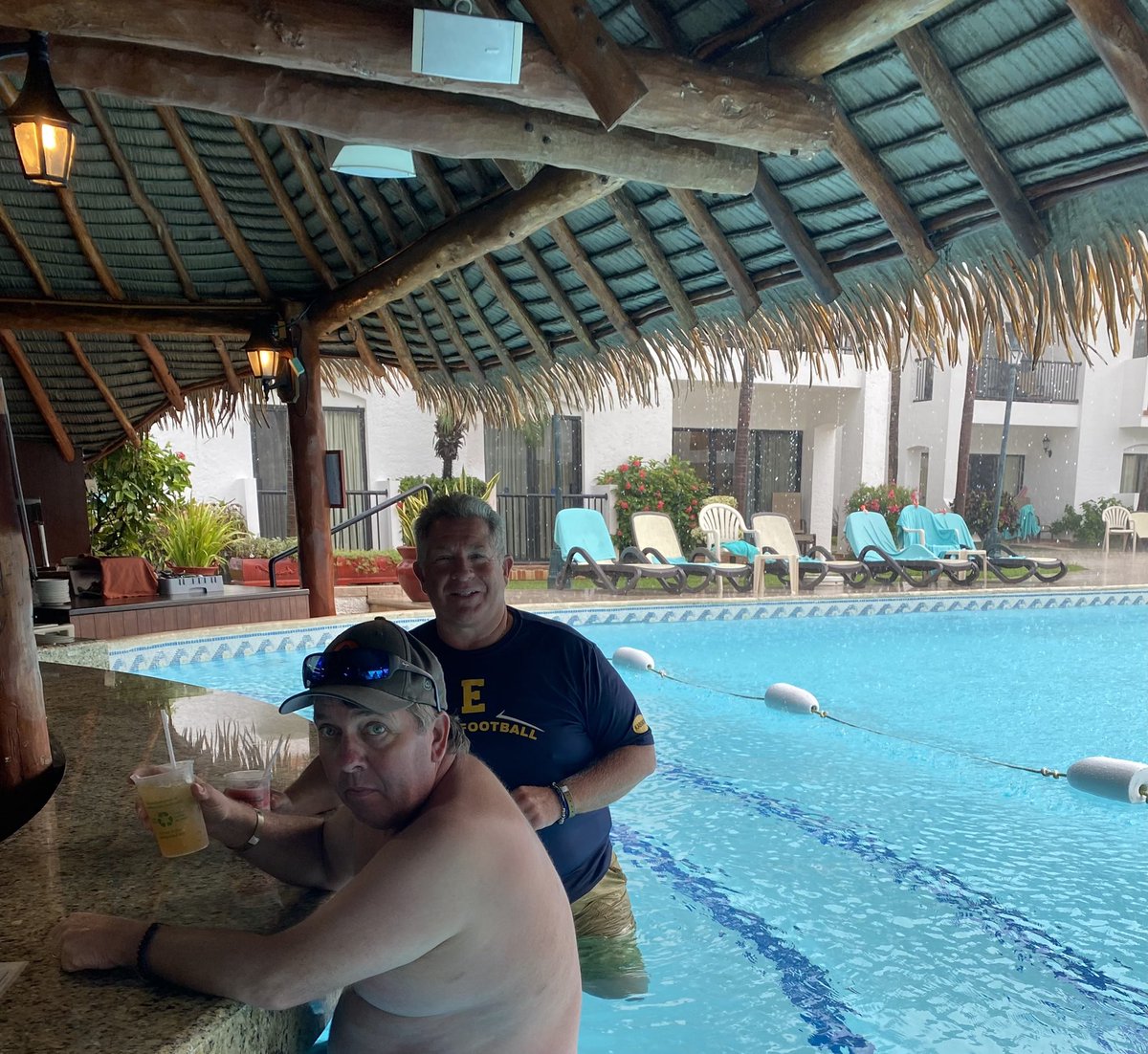 EGRAD5's tweet photo. When it rains in Cancun (not very often). You find cover with a friend and a cervaza!!#retirementisgood https://t.co/EnroHubrkl