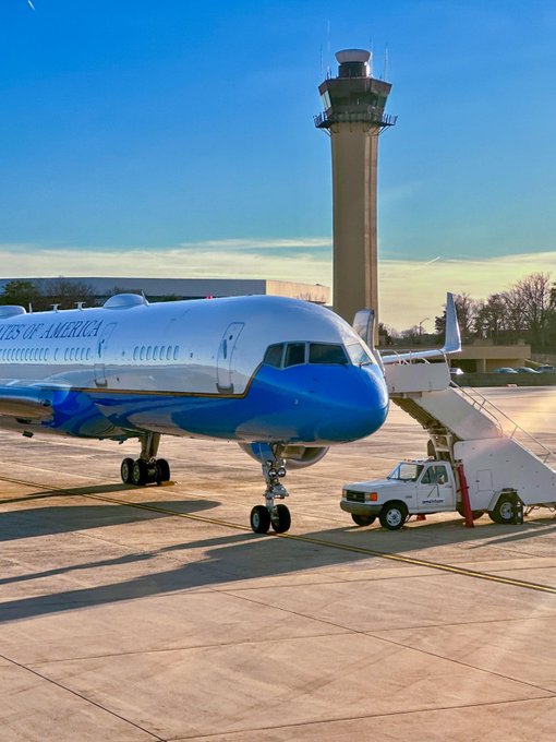 The Secretary's plane is on the airport tarmac with clear blue skies in the background.