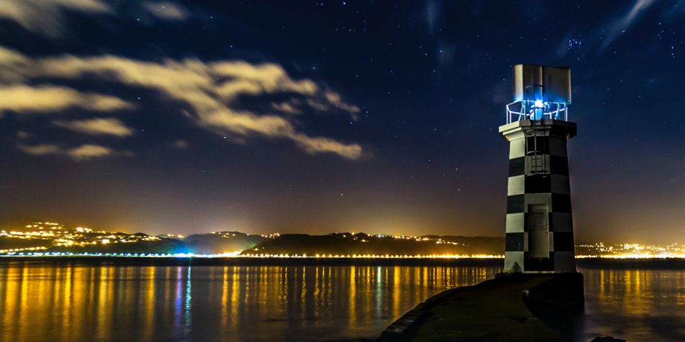Photo of Ed and Stede's lighthouse at night with the city in the background 