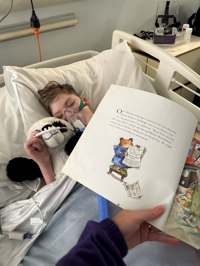 jessiemaytrust's tweet photo. A gentle moment between Jessie May nurse Bryony and Logan:

"Here is a picture of Logan while in hospital recovering from a chest infection, Logan enjoyed me reading Paddington bear which sent him to sleep, during this time mum managed to get out for some fresh air and food." https://t.co/9qZ1EV5tiS