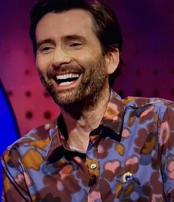 thinktennant's tweet image. david tennant wearing a non-binary pin on the last leg (2023)