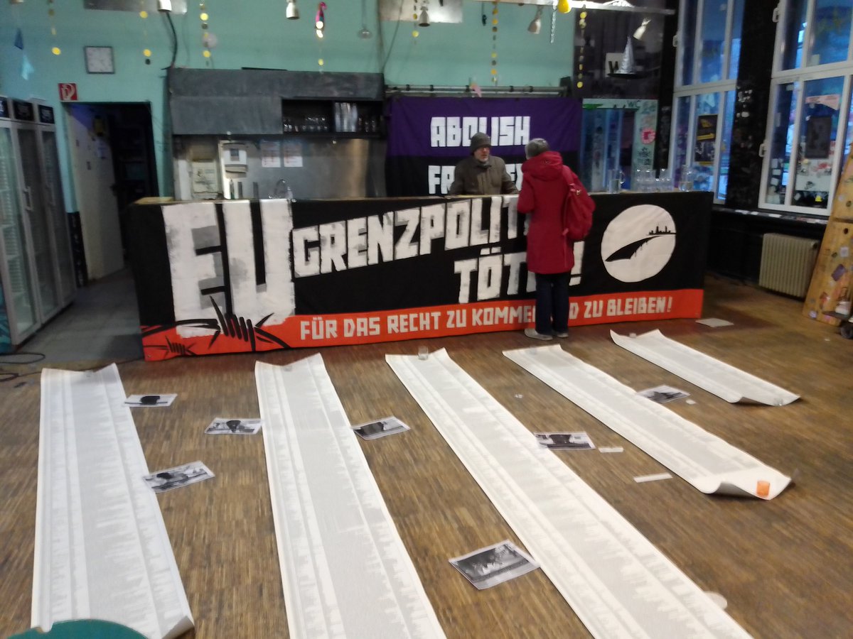 An einem Tresen hängt ein Transpi 'EU GRENZPOLITIK TÖTET!'<br>Dahinter an der Wand 'ABOLISH FRONTEX'