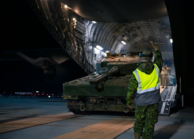 A Leopard 2 main
                                              battle tank donated by
                                              Canada to Ukraine is
                                              unloaded from a Royal
                                              Canadian Air Force CC-177
                                              Globemaster III aircraft
                                              in Poland. A Canadian
                                              Armed Forces member in a
                                              safety vest is visible in
                                              the foreground, providing
                                              hand signals to assist
                                              with the unloading.