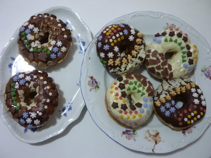 Six chocolate glazed 🍩 decorated with tiny cocoa star and vanilla men biscuits, almond and different types of chocolate flakes and tiny snowflake, tree and star shaped sugar decorations. A bit of pecan crumble on one of them. Two are glazed with dark chocolate, two with white chocolate and two with white chocolate mixed with blood orange juice, resulting in an orangey chocolaty glaze.
