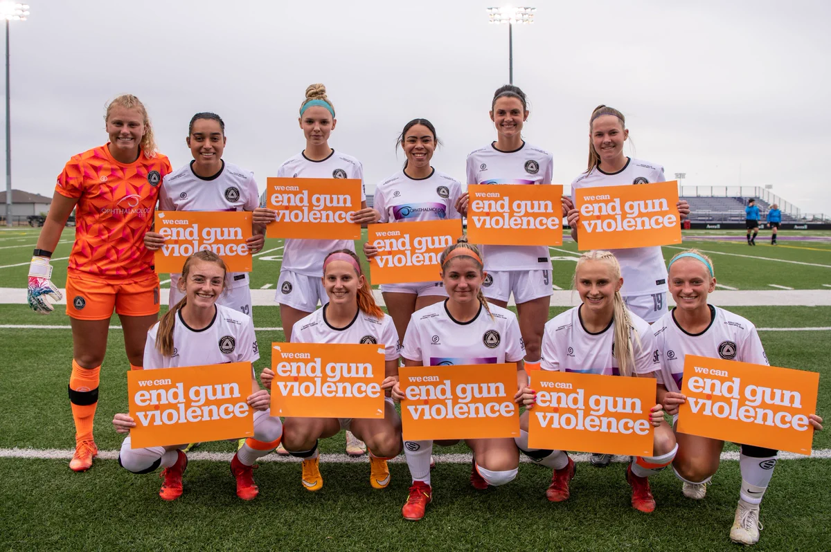 Sioux Falls City FC's 2022 home opener's starting XI holding orange signs that read "we can end gun violence".
