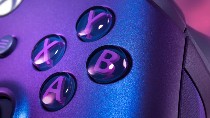 La imagen muestra un primer plano angular del lado derecho del mando inalámbrico Xbox Stellar Shift sobre un fondo de galaxia rosa y morado. En el centro están los botones gris azulado del lado derecho, y las letras "RB" y "RT" son claramente visibles. El plástico transparente de los botones Y y B, así como el joystick derecho, también son visibles desde el lateral. El brillo iridiscente azul y morado del mando está presente y a la izquierda del marco se aprecia un indicio del dibujo de la nebulosa en la empuñadura texturizada.