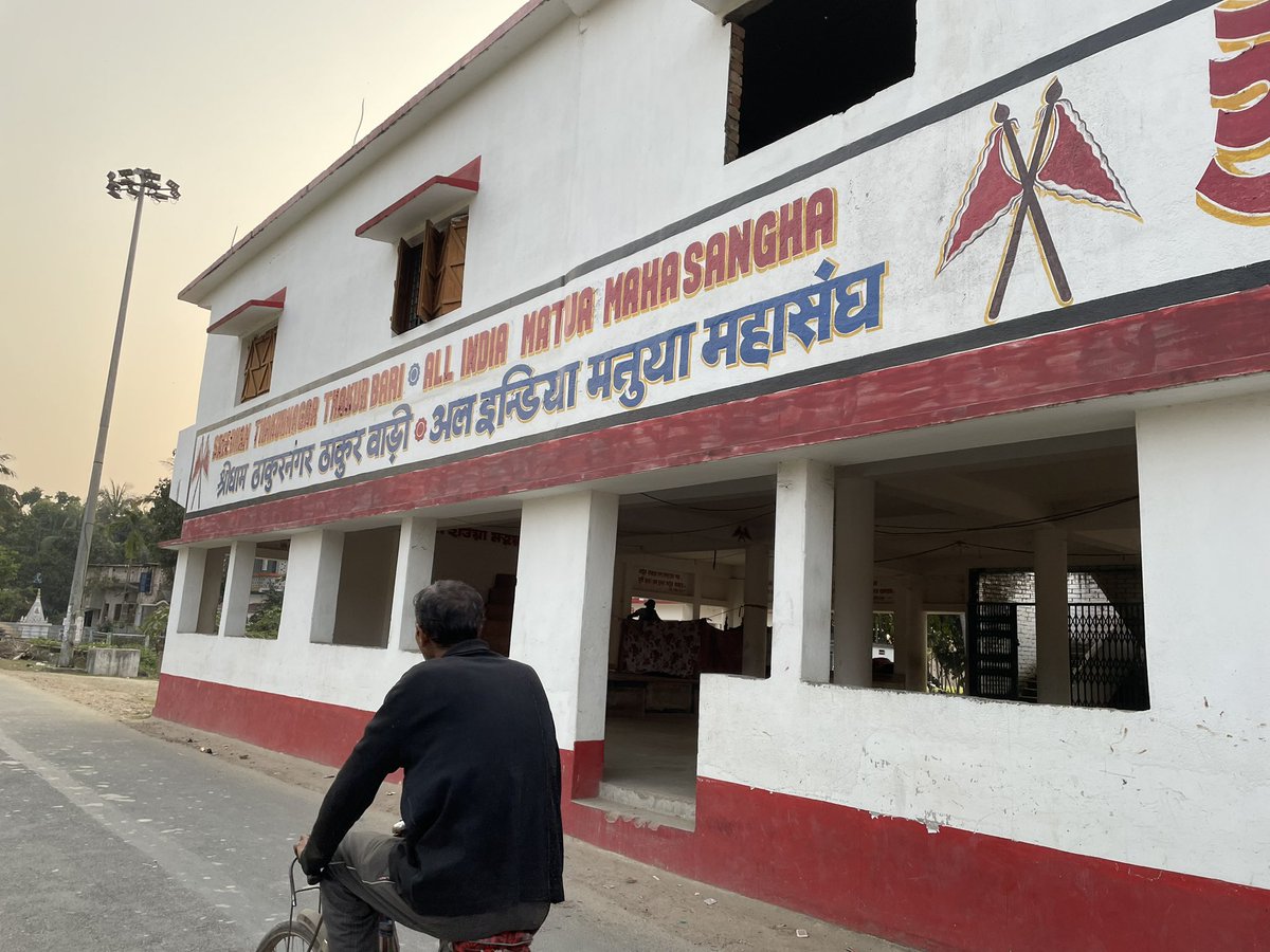 🇮🇳 भारत और बांग्लादेश 🇧🇩सीमा पर आज की ढलती शाम और मैं। मातुआ महासंघ के लोगों से नागरिकता और अन्य प्रश्नों पर बातचीत। विशाल ठाकुरबाड़ी के दलित पुजारी। मंदिर में गुरुचांद ठाकुर और गुरू माँ की मूर्ति। दीवार पर लिखा है- “घर में खाना न हो, कोई बात नहीं, पर बेटी-बेटे को ज़रूर पढ़ाओ।”