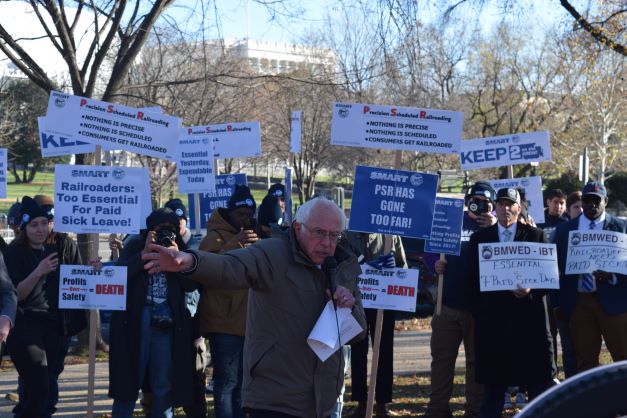 Senator Bernie Sanders speaks in front of a group of railroaders holdings signs, protesting against precision scheduled railroading.