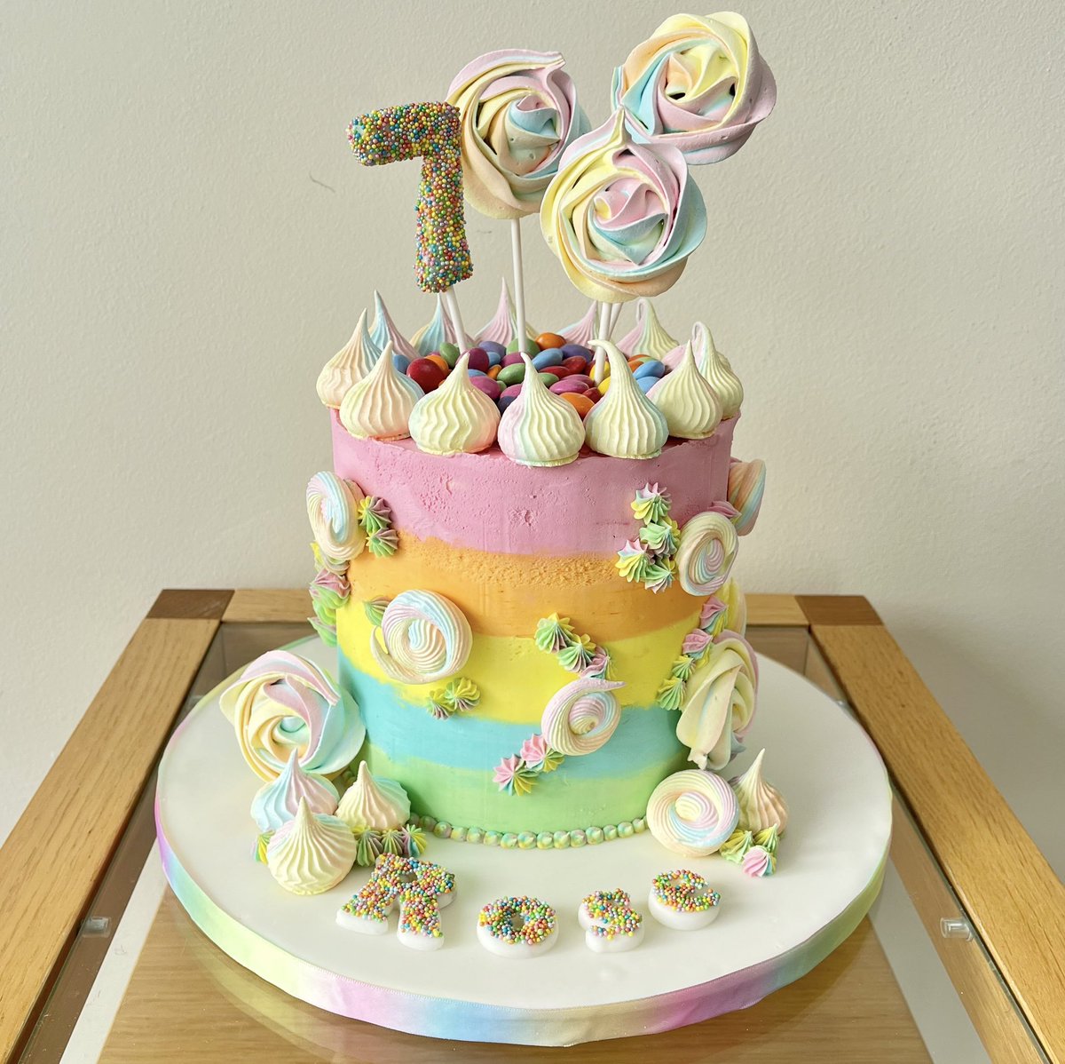Rose had this very same design mid lockdown two years ago and wanted the same again to share with her friends! Vanilla sponges with pastel rainbow buttercream stripes and meringue kisses and lollipops make this a very colourful cake.