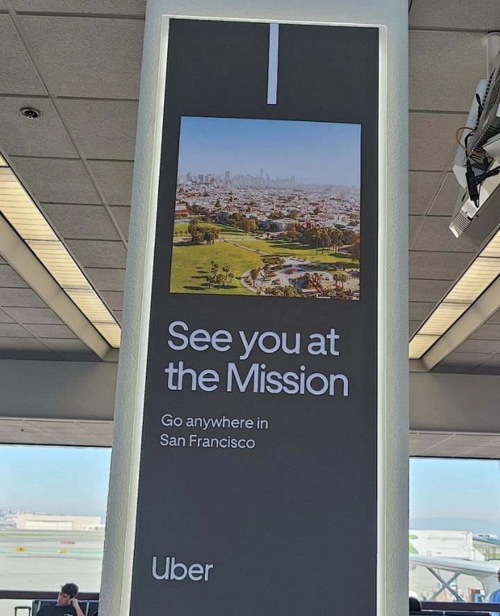 pitdesi's tweet photo. Uber ads at SFO seemingly written by people who have never been to San Francisco… no one here talks like this. 
Would be “at the Embarcadero”
“In the Mission”
“in the Marina” which btw doesn’t look like that - it’s a picture of Sausalito!

Who do we think designed these ads??? https://t.co/vZgY9OYOKL