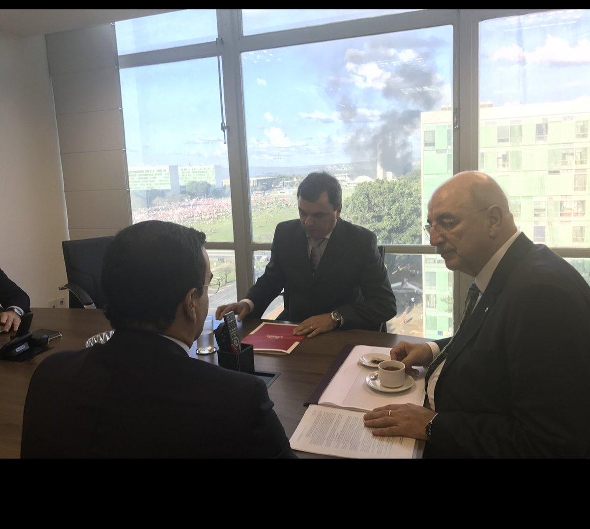OsmarTerra's tweet photo. Aqui despachando no Ministério do Desenvolvimento Social no fatídico dia 24/05/2017, com fumaça  dos incêndios dos Ministérios ao fundo! https://t.co/h0L9bg30mB
