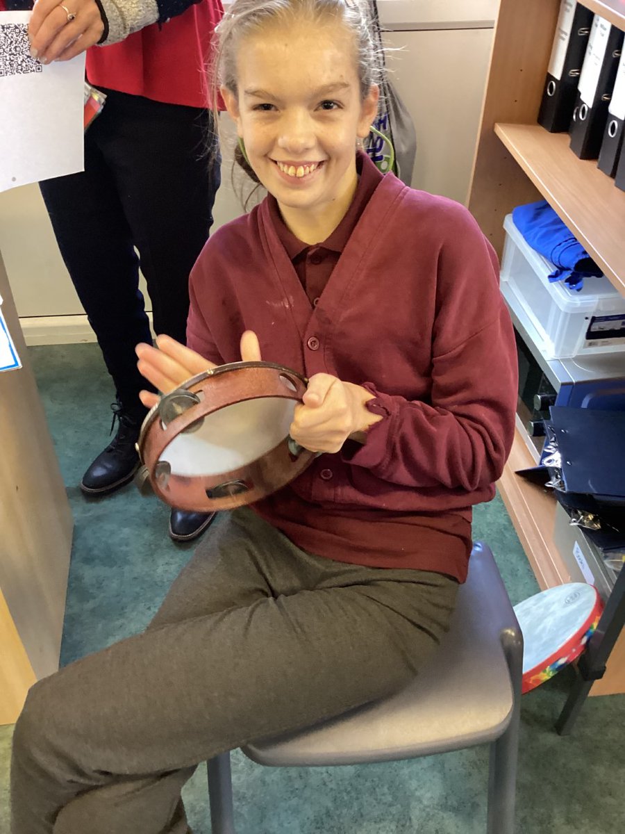 During the music workshop, children have the chance to play various musical instruments. Here is a picture of a joyful workshop participant in a special education school, playing her tambourine with a big smile on her face.