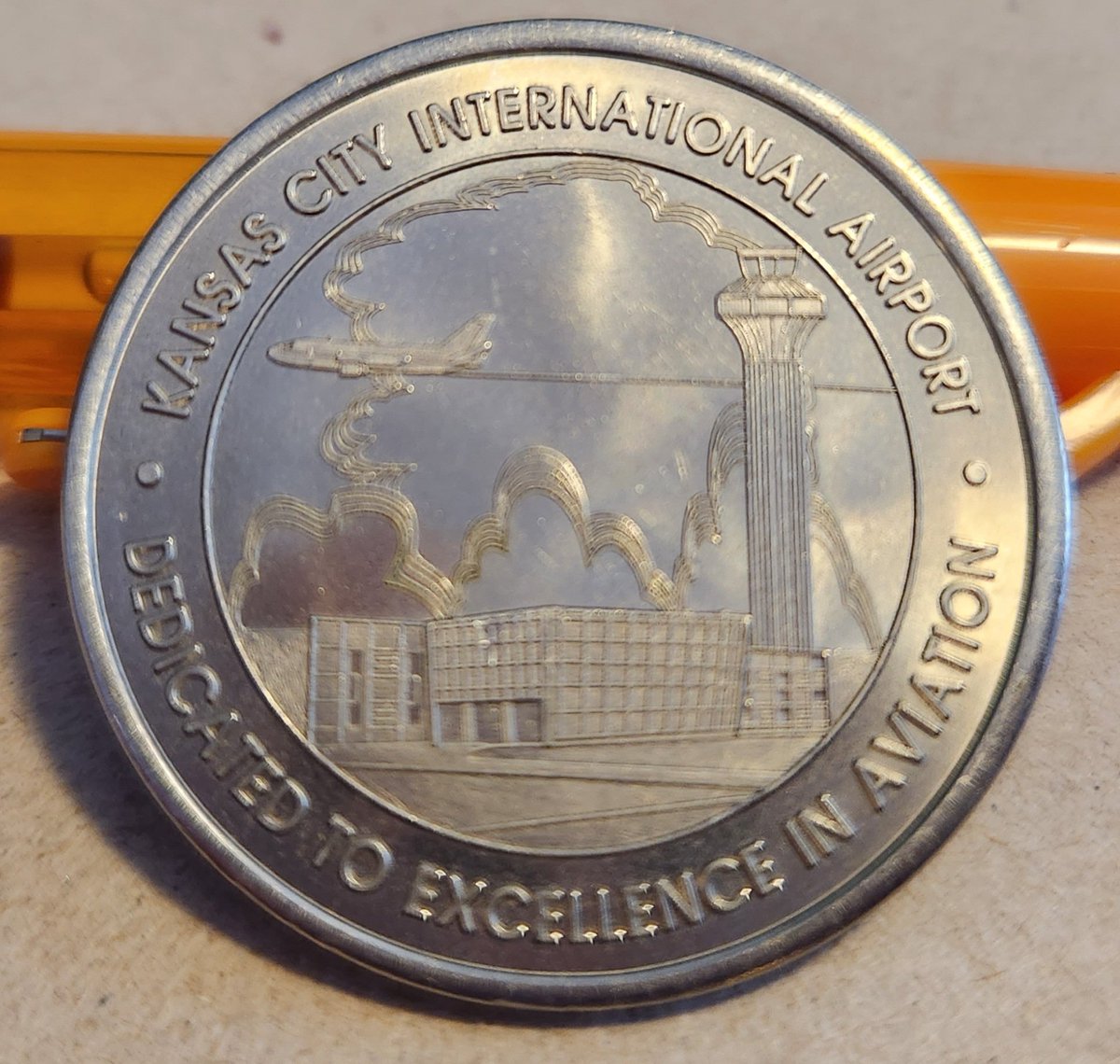 LDKnise's tweet photo. Going through some of parents stuff and came across this little gem. The silver anniversary coin for the current KCI airport.  My Dad worked for Continental Airlines for 34 years.  He worked at the old downtown airport and the current airport.  #FlyKCI #BuildKCI https://t.co/TM6T19kEwL