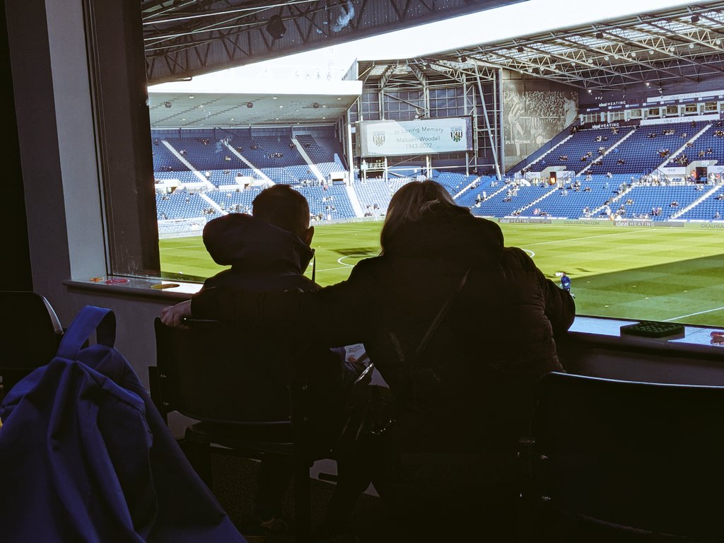 A mum and son looking out to the pitch from a sensory room.