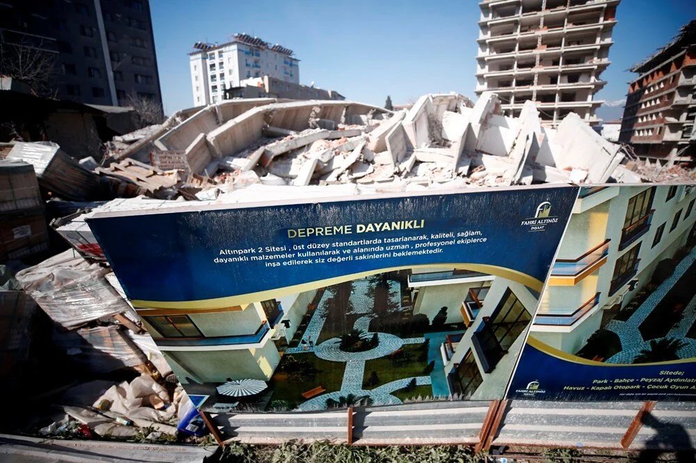 In front of one of the collapsed buildings in the earthquake, still stands the advertisement for the building: "Withstands Earthquake."