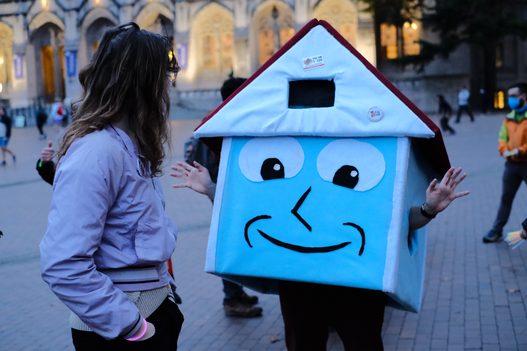Housey making a gesture with open hands to a person facing away from the camera