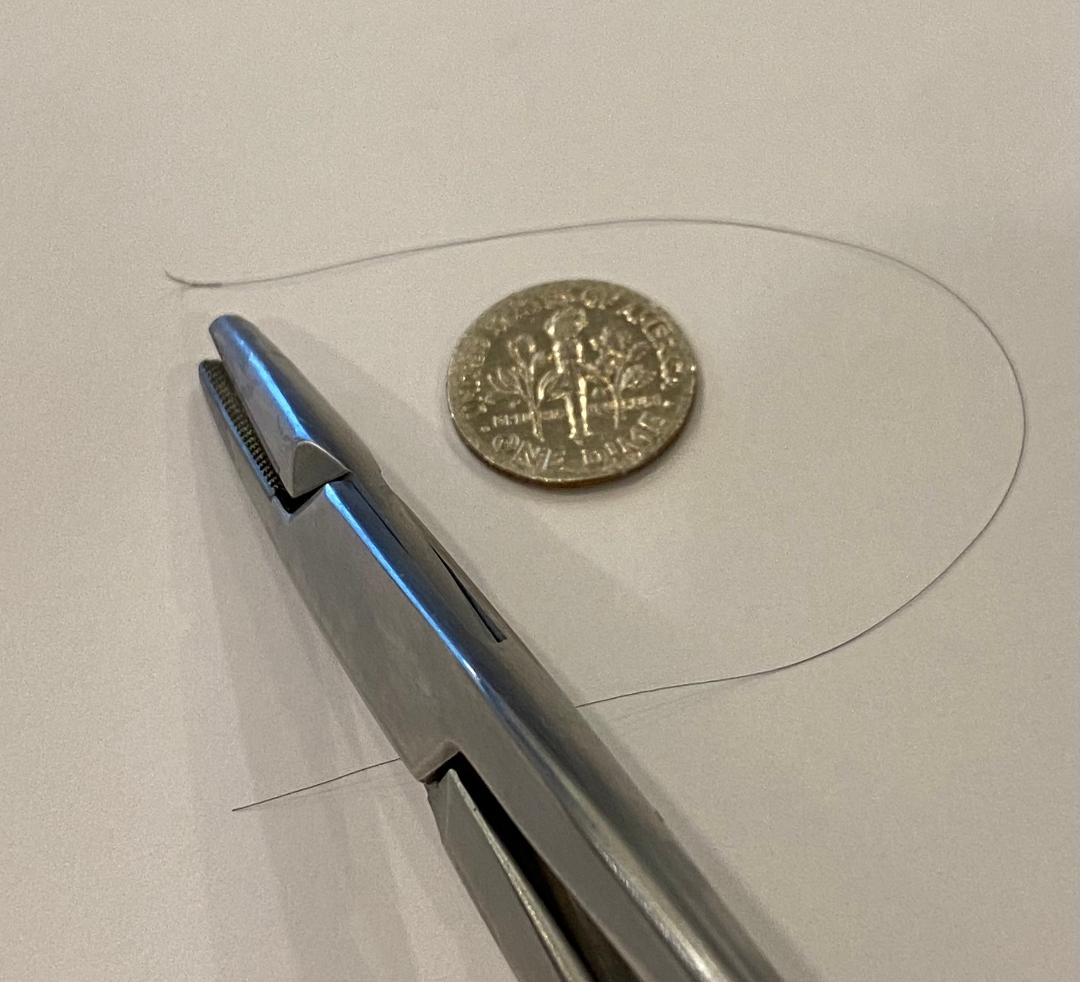 Here is an 8-0 Nylon on one of the smallest needles, next to a standard size needle holder (which you wouldn't use) for reference.

8-0 Nylon is used in ophthalmologic procedures, and I also found references describing its use in peripheral nerve surgery and for vasovasostomy.