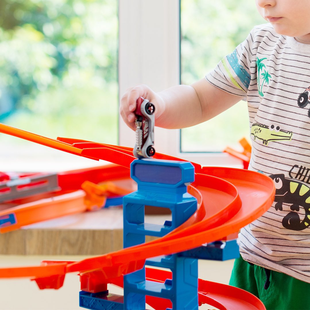 Child playing with Hot Wheels on a track at home.