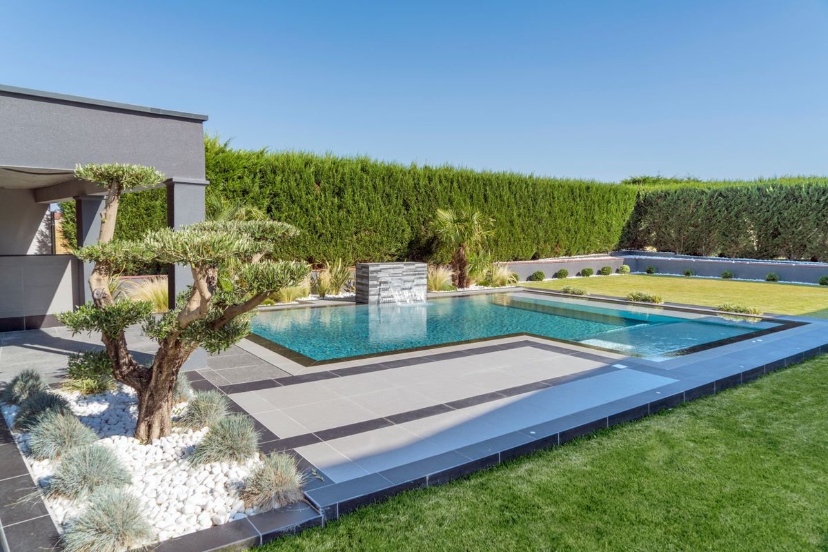 Voici une magnifique piscine design en parfaite adéquation avec la maison d’architecte.

Du revêtement minéral gris avec option scintillante aux bords miroirs sur toute la périphérie du bassin, cette piscine reflète parfaitement les piscines tendances.