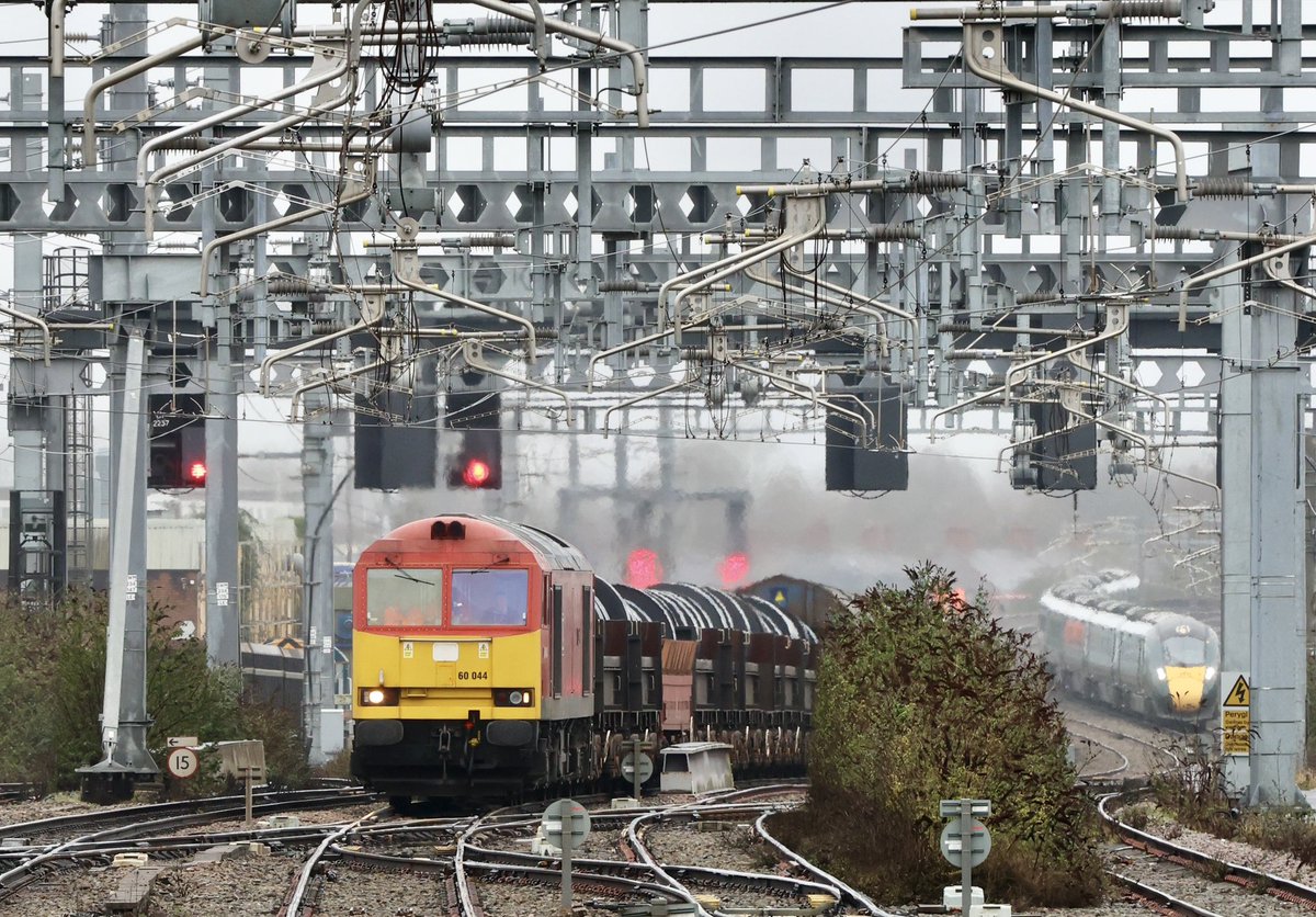 Derbyshire Grit on Welsh Steel. 60044 ‘Dowlow’ powers the 6H25 Margam-Llanwern steel coils up the gradient into Cardiff Central station, whilst 800312 performs a platform move in the background. 16 February 2023.