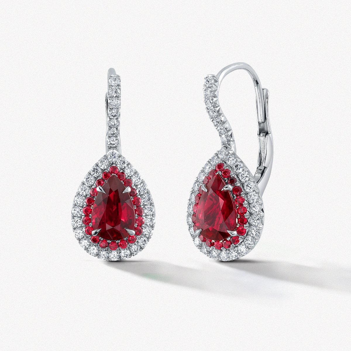 The quintessential pair of classic ruby and diamond drop earrings. Zoom in to see the hand-set details seen in the duet halo. The color of the expertly matched pair of rubies are of the finest quality. Message us for more information on how you can see these in person!

E1346