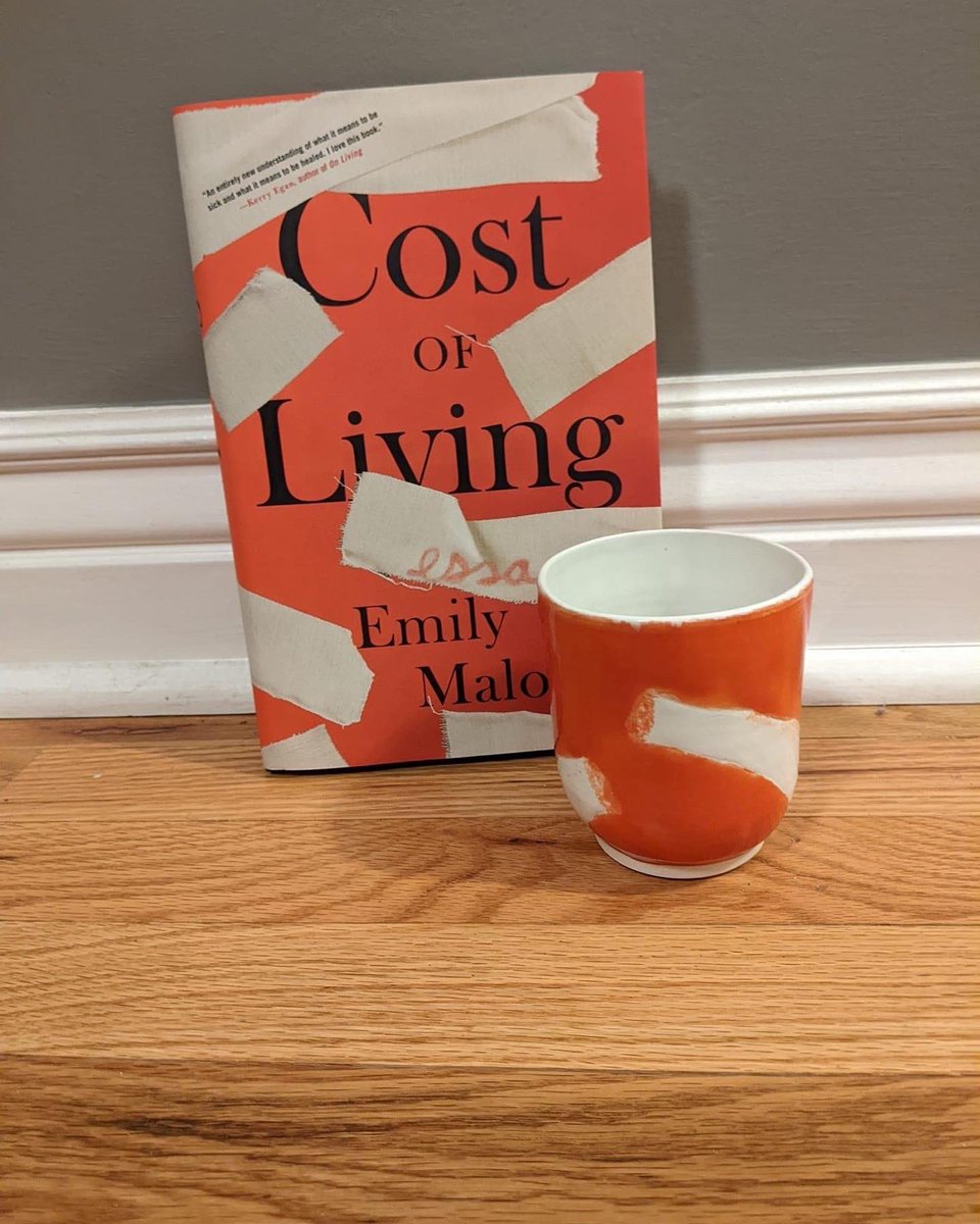 Cost of Living the book next to a cup that resembles it.