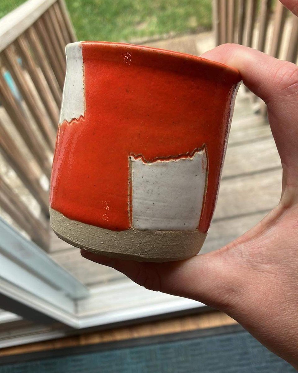 Orange cup with white “bandages” on it held to the light. There are exterior deck stairs behind.